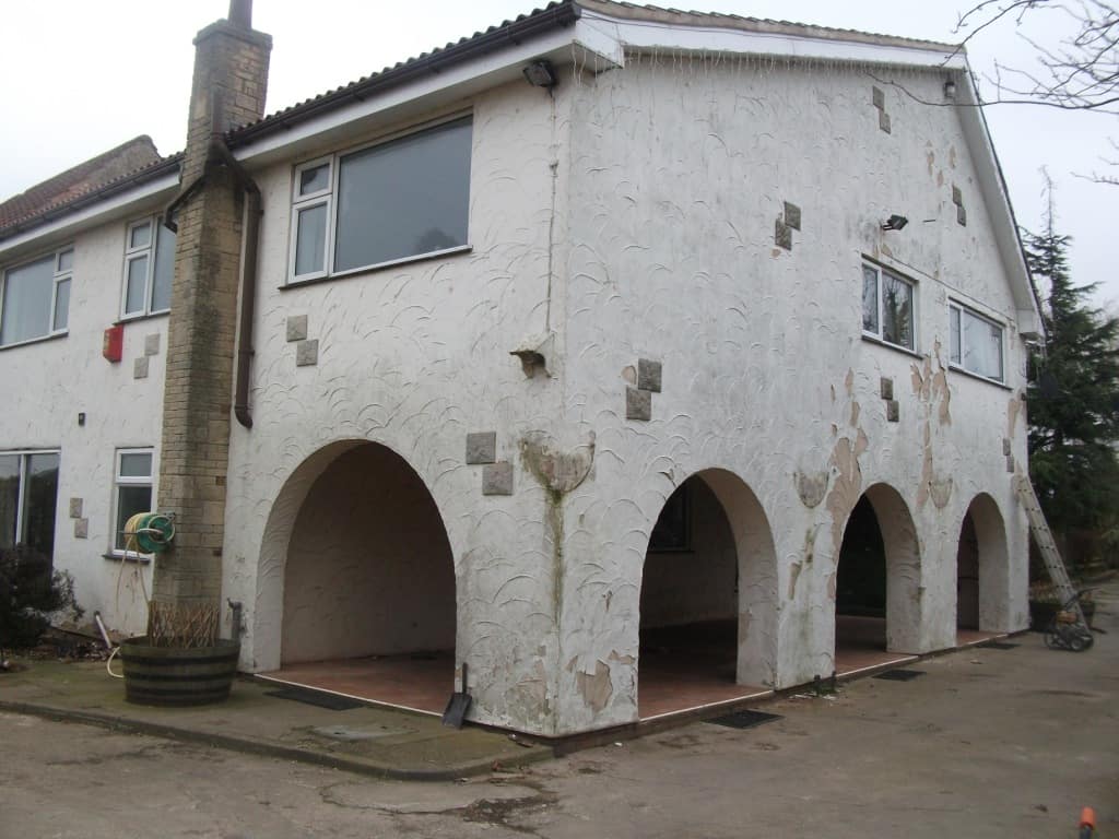 A rendered house with extensive flaking paint A rendered house with extensive flaking paint