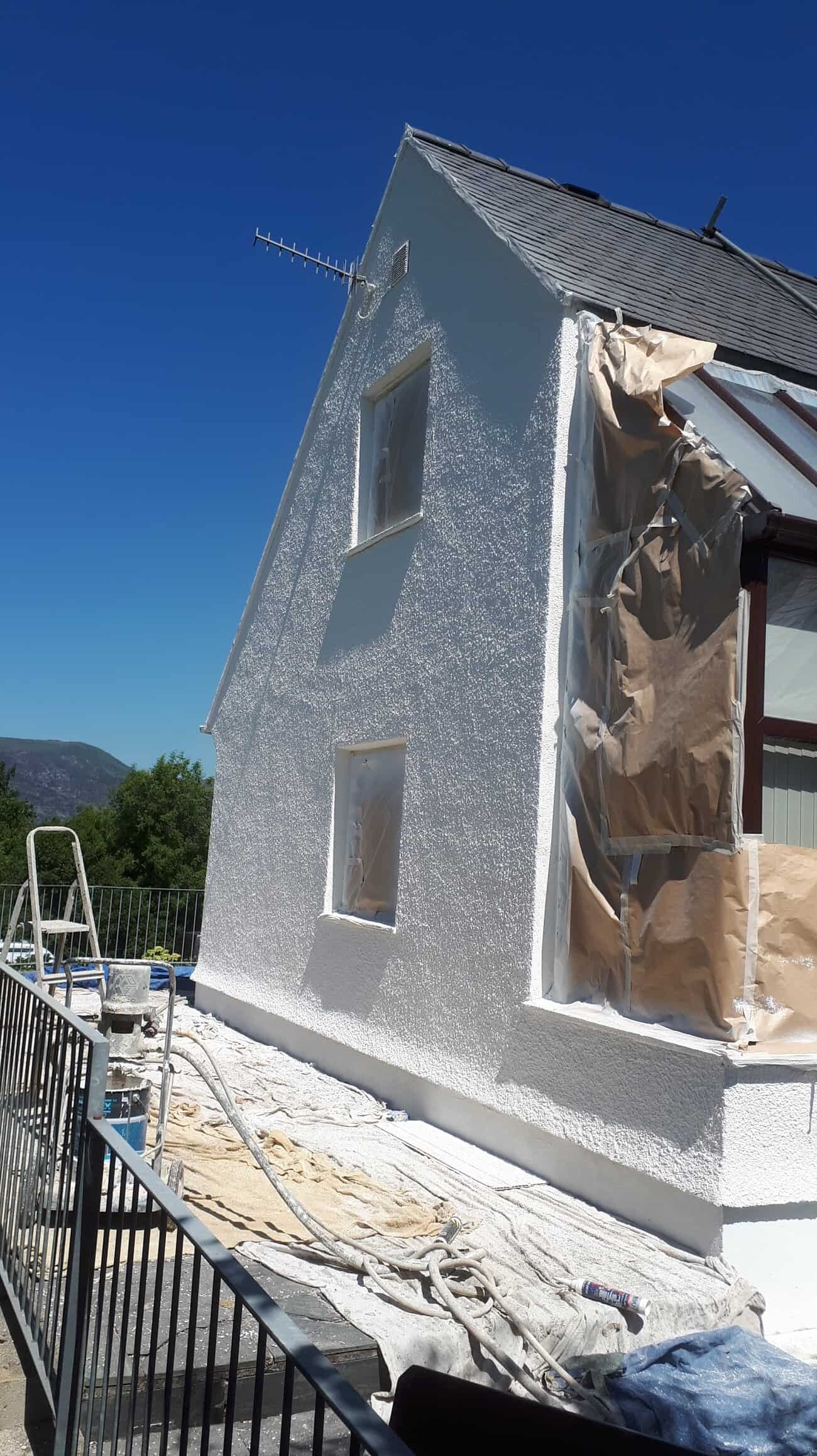 Gable end wall being sprayed with exterior wall coating-min