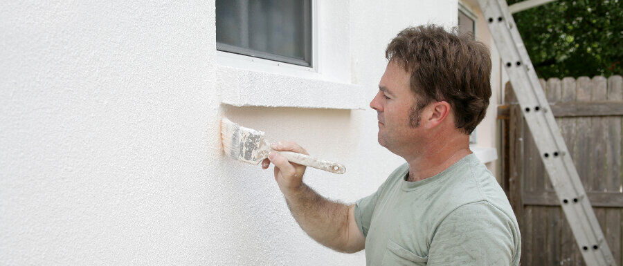 man painting exterior brick walls