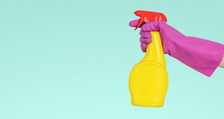 person holding a bottle of cleaner and a rubber glove