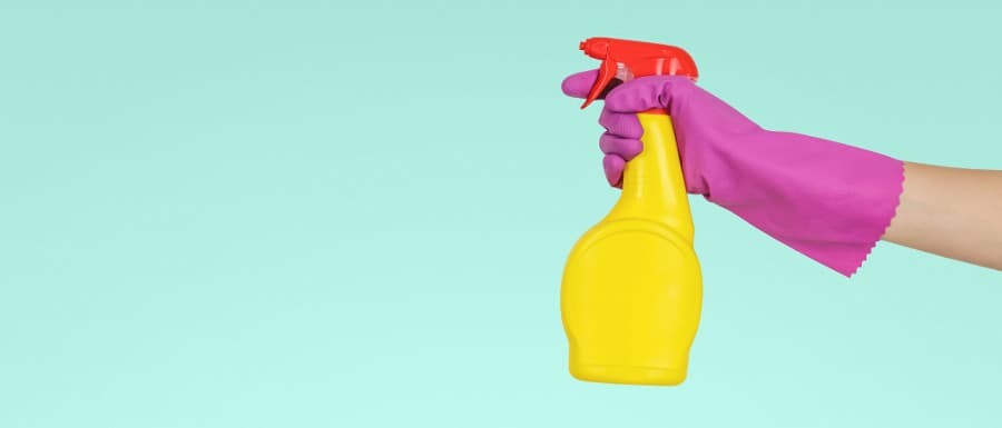 person holding a bottle of cleaner and a rubber glove